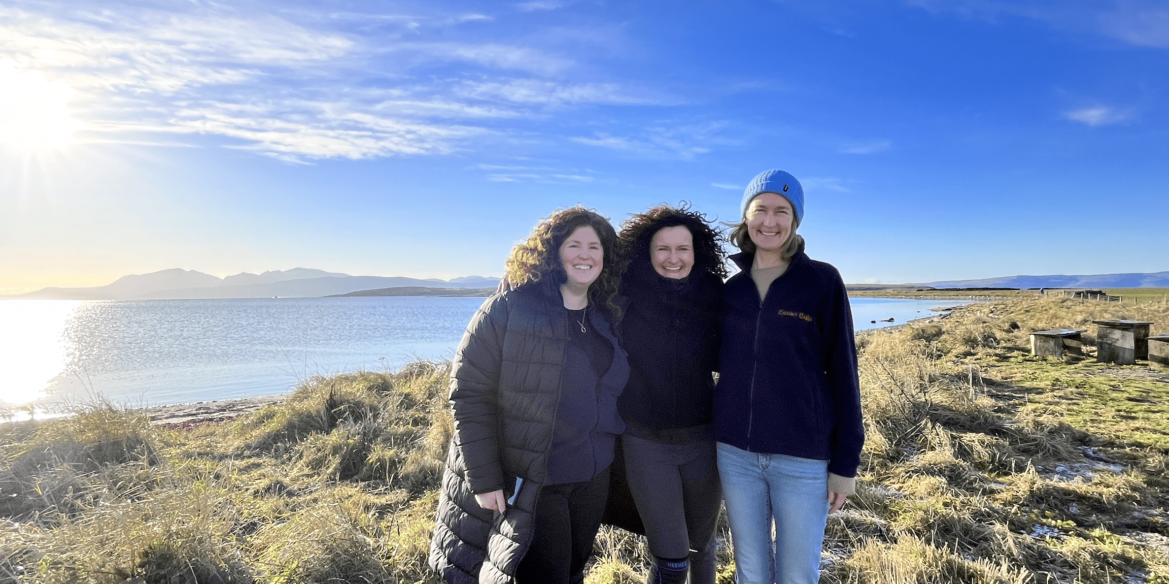 Elaine and Calum's Cabin team Three women stand together smiling, on a crisp wintery day.