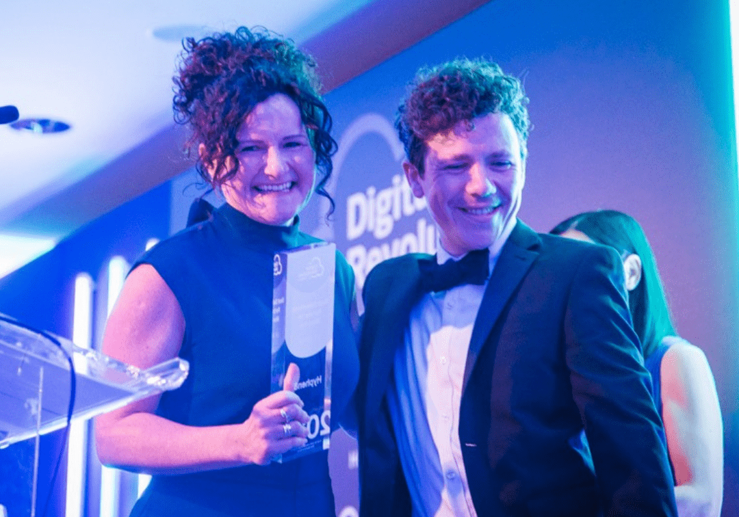 Man and Women smiling leave stage with an award at the Digital Revolution awards.